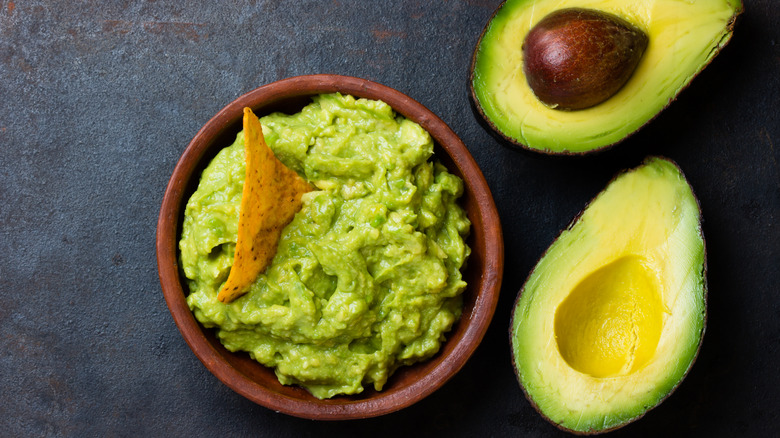 Side-by-side display of fresh avocados and a bowl of guacamole
